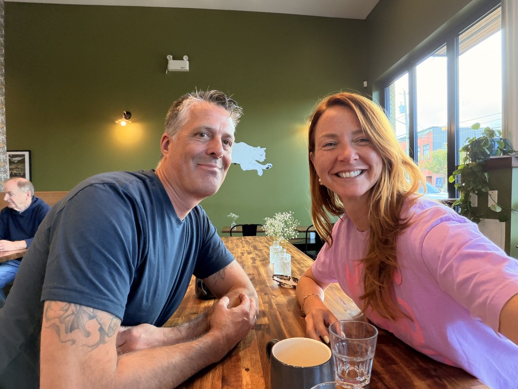 Two members smiling over coffee at a green-walled cafe